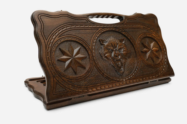Carved beechwood backgammon board with a fierce wolf between carved stars, propped open