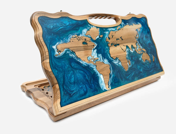 Folding backgammon board with a world map - wooden continents set in swirling blue and teal epoxy oceans - standing open with a carved carry handle