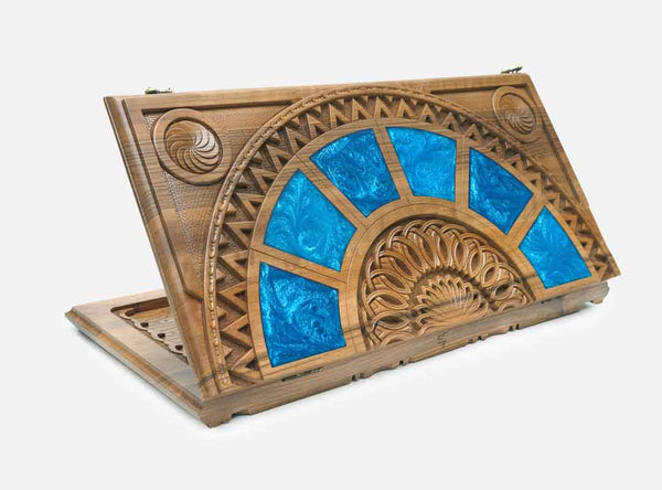 Folding wooden backgammon board with blue epoxy panels around the carved Eternity Sign, shown closed at an angle
