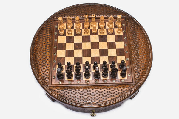 Round wooden chess set with woven lattice-carved border and wooden pieces set up on the inlaid board