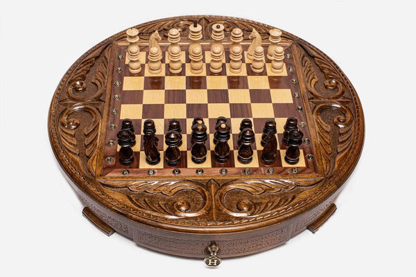 Round handmade wooden chess set with walnut and maple inlaid board and carved pieces set up for play
