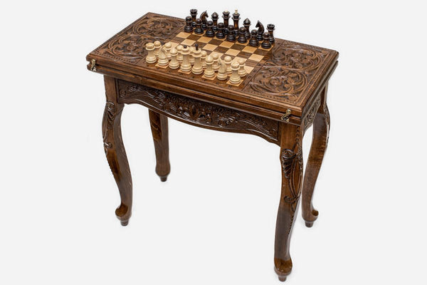 Scrollwork chess and backgammon table set up for chess, angled view of the carved legs