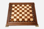 Carved wooden chess set shown folded with bronze clasps