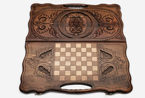 Abu Dhabi backgammon set laid flat, carved emblem face above and inlaid chequered face below, a carry handle in each half
