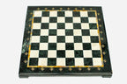 Top-down view of the empty green and cream marble chess board with an amber onyx inlay and brass markers
