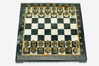 Angled overhead view of the green marble chess board with bronze pieces set up for play