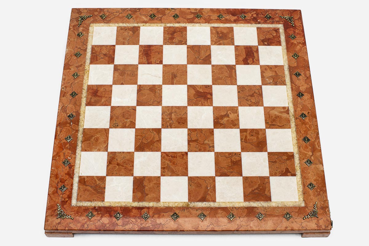 Top-down view of the empty coral and cream marble chess board with brass coordinate markers