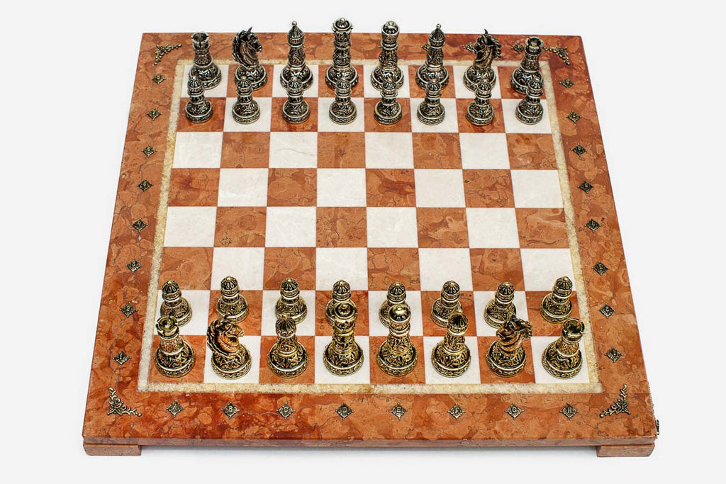 Row of the two-tone bronze chess pieces showing kings, queens, bishops, horse-head knights and rooks