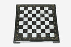 Top-down view of the empty burgundy and white marble chess board with a grey border and brass coordinate markers