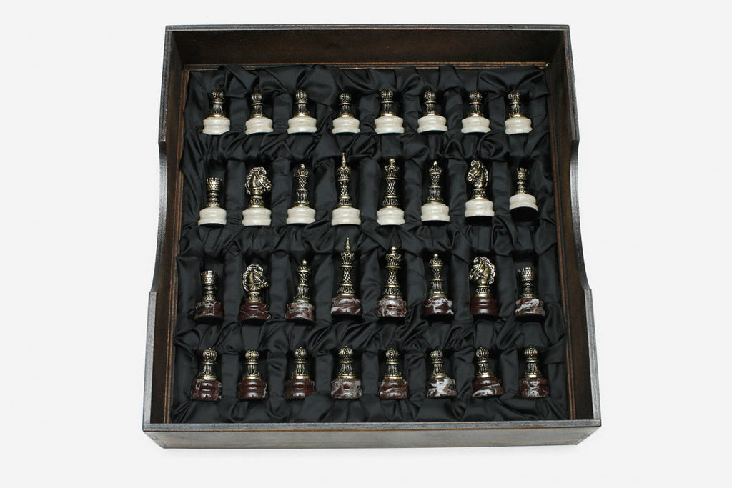 Bronze chess pieces with marble bases arranged in the black satin-lined wooden box