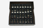 Bronze chess pieces with marble bases arranged in the black satin-lined wooden box