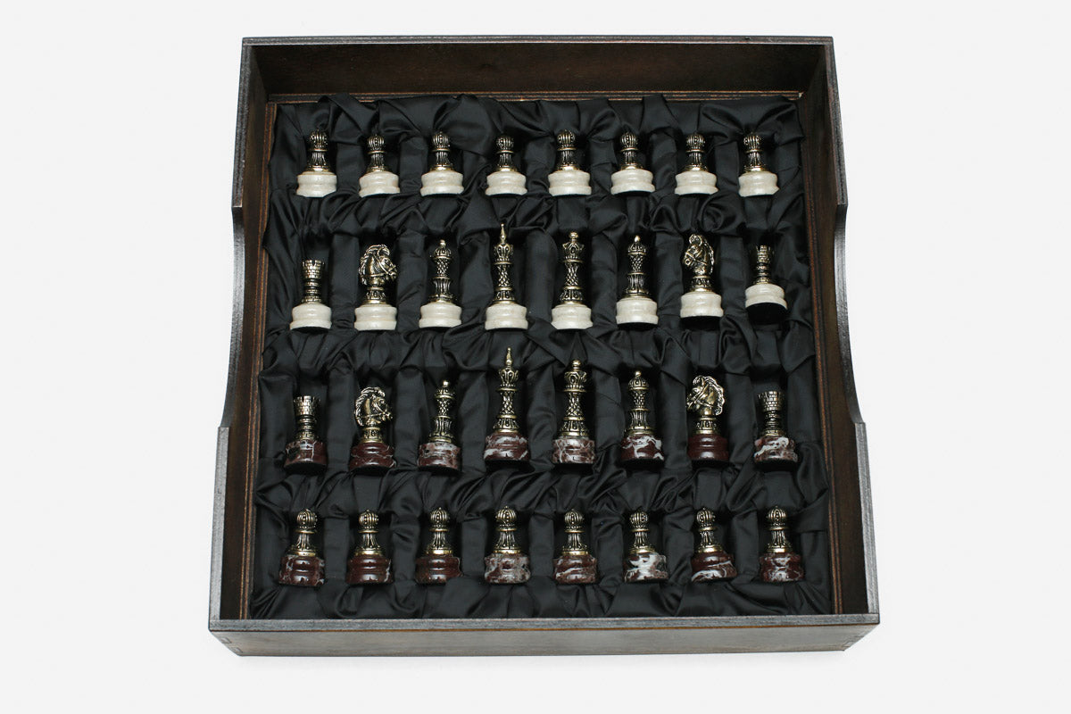 Bronze chess pieces with marble bases arranged in the black satin-lined wooden box