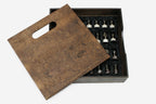 Wooden carry box with slot handle open beside the marble chess set, pieces resting in black satin