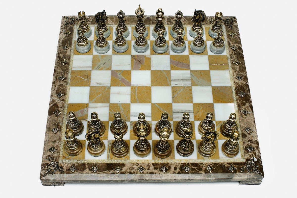 Golden marble chess set with hand-cast bronze pieces arranged for play and brass coordinate markers