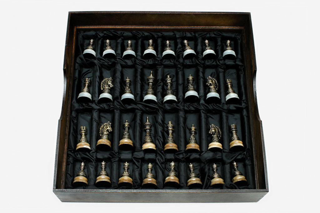 Cast bronze chess pieces on the golden and white marble board