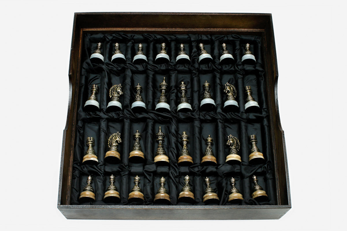 Cast bronze chess pieces on the golden and white marble board