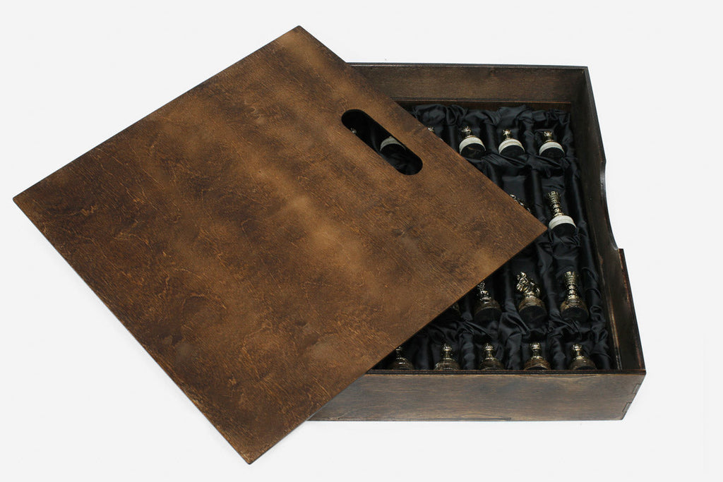 Wooden storage box open beside the marble board, showing the bronze chess pieces wrapped in black satin