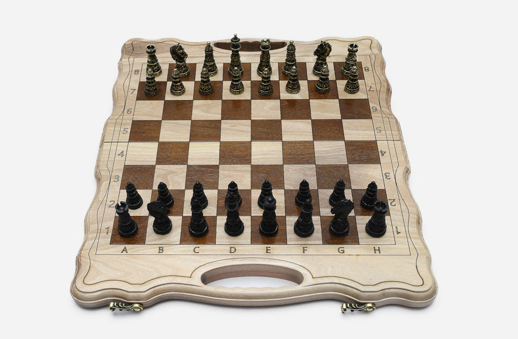 Luxury classic walnut chess set with ornate bronze pieces, the gold army facing the black army in starting position