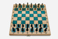 Folding chess board in pale wood with teal epoxy squares and ornate bronze figural pieces - gold and black armies in starting position
