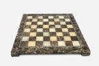Elevated angle of the polished brown marble chessboard with its brass-studded border
