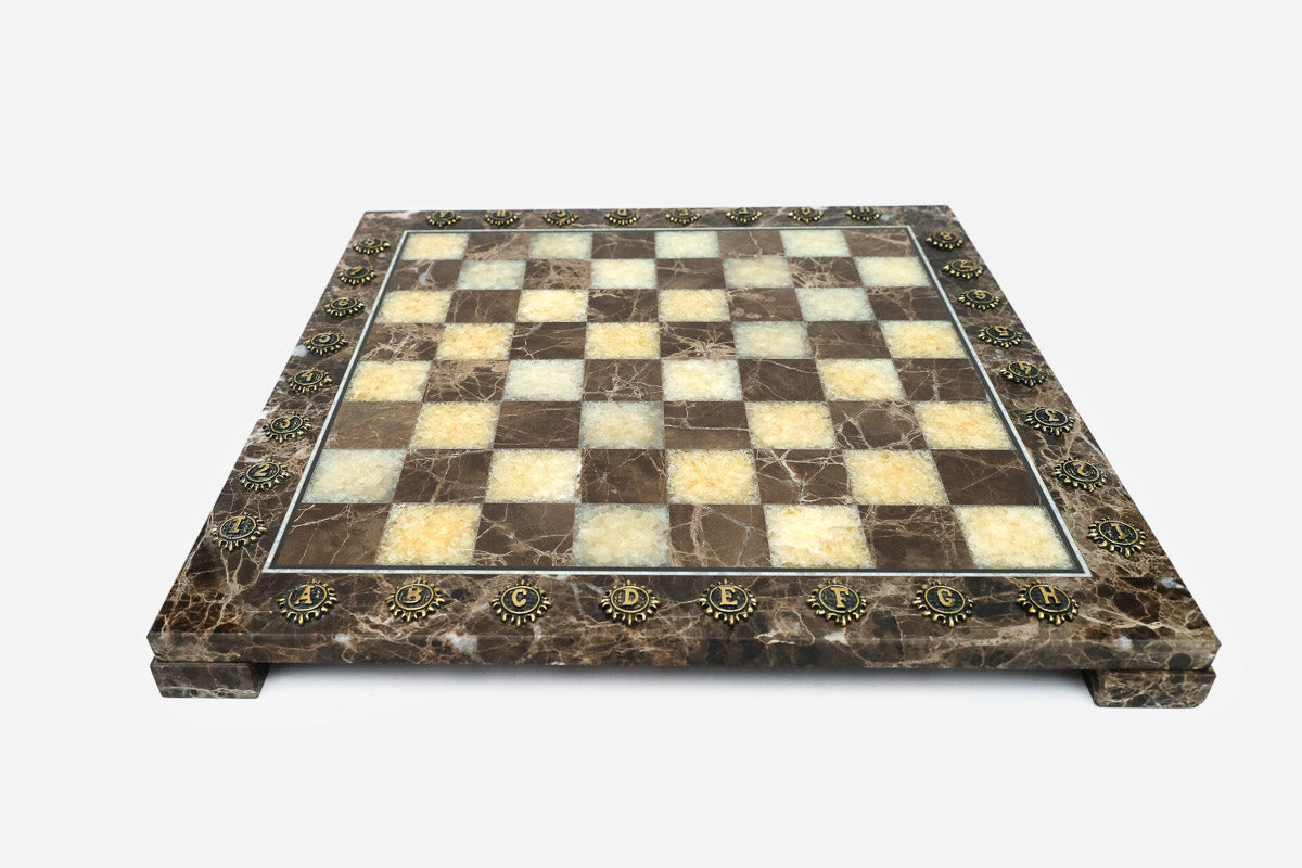 Front view of the brown marble chess board framed by brass letter and number markers