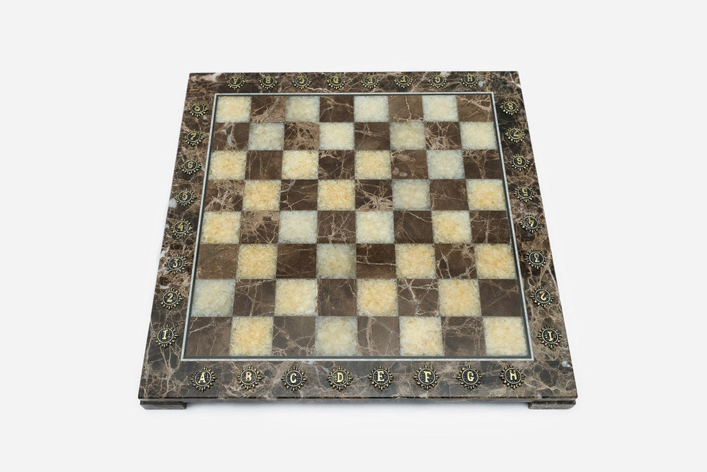 Top-down view of the empty brown and cream marble chess board with brass coordinate markers
