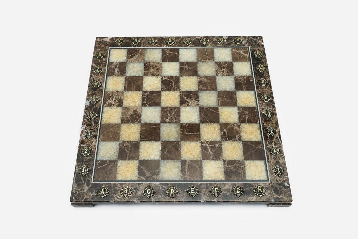 Top-down view of the empty brown and cream marble chess board with brass coordinate markers