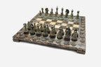 Angled view of the brown marble chess board with detailed bronze pieces set up for play
