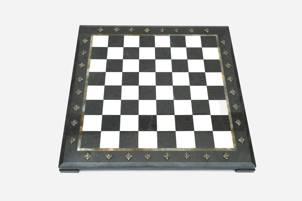 Top-down view of the empty black and white marble chess board with brass coordinate markers