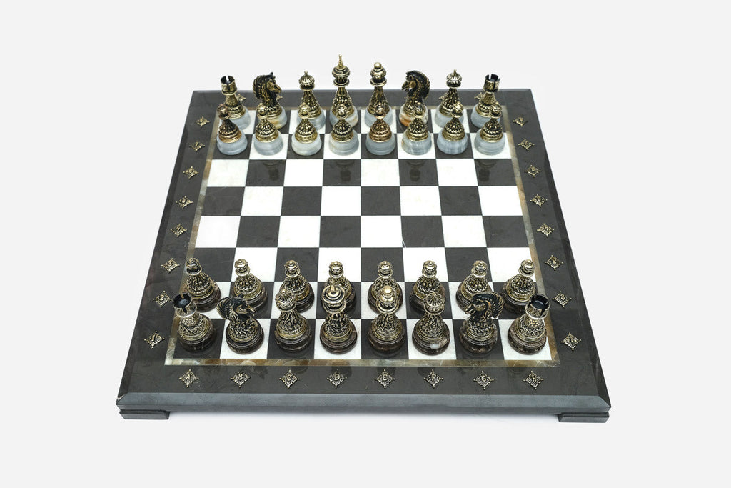 Elevated angle of the black marble chess board with bronze pieces and brass coordinate markers