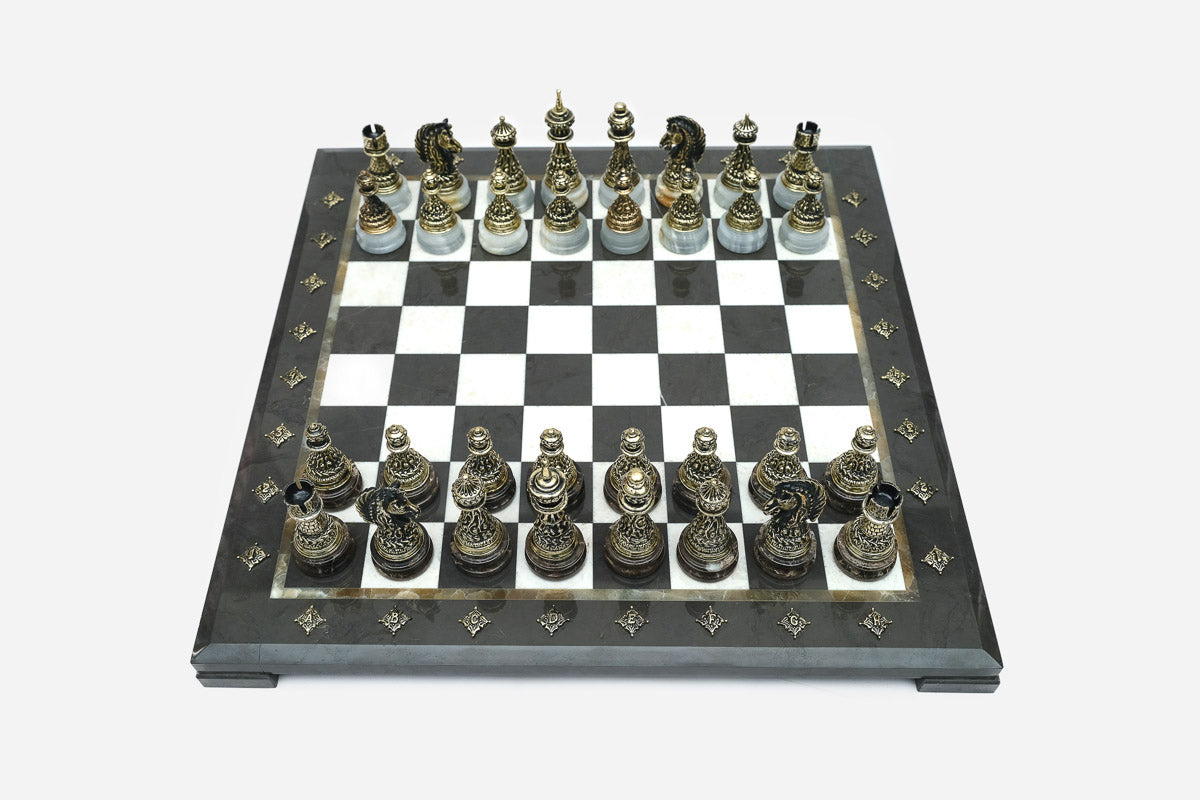 Elevated angle of the black marble chess board with bronze pieces and brass coordinate markers