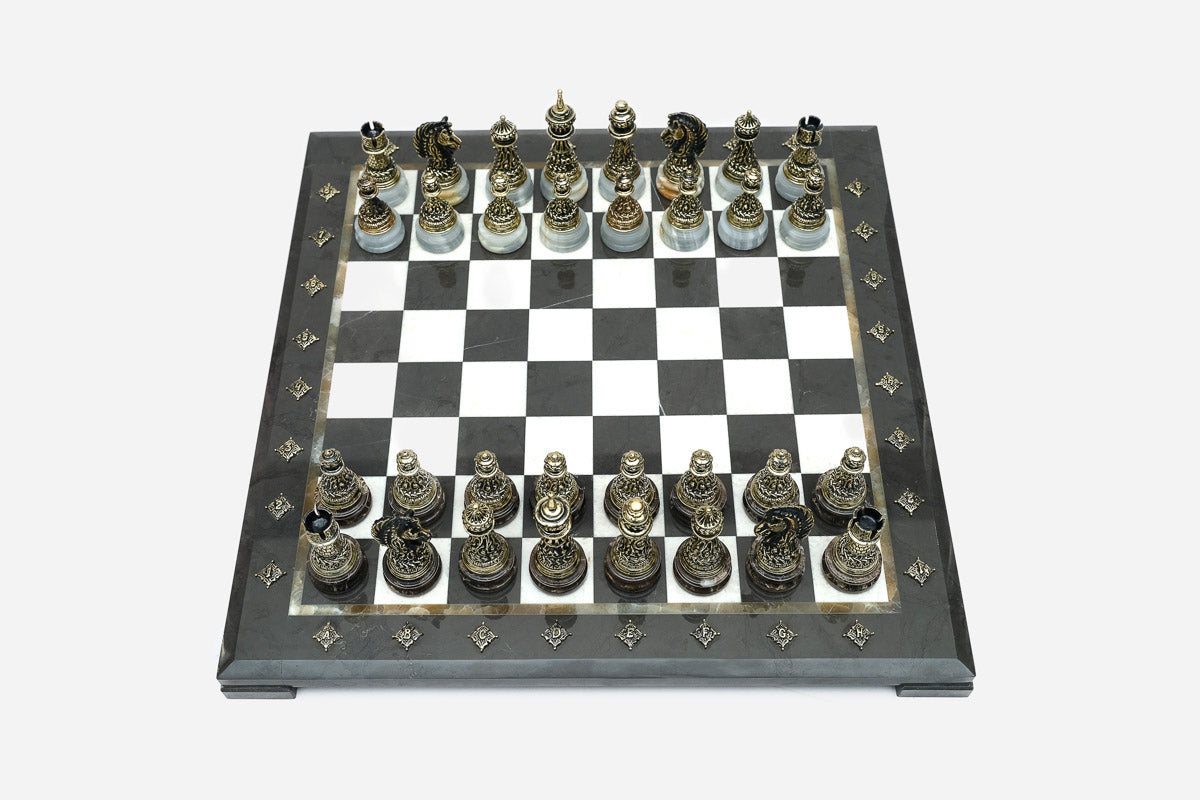 Black and white marble chess set viewed from the front with bronze pieces ready to play