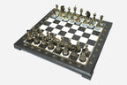 Angled view of the black marble chess board with detailed bronze pieces set up for play