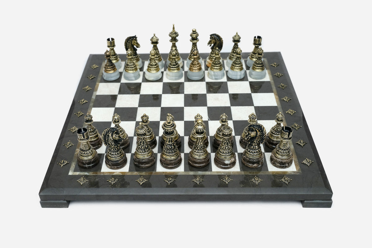 Black marble chess set with hand-cast bronze pieces arranged for play and brass coordinate markers