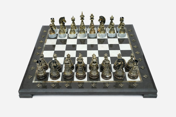 Black marble chess set with hand-cast bronze pieces arranged for play and brass coordinate markers