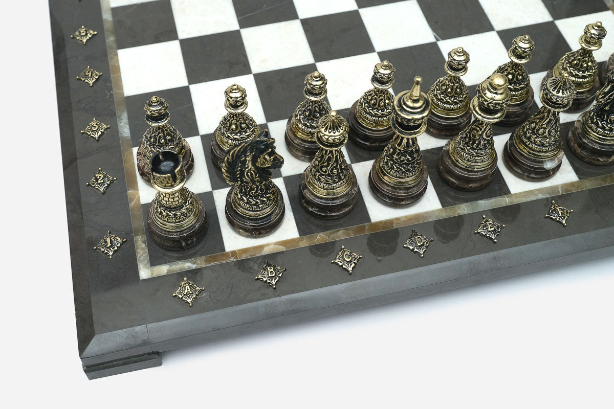 Close-up of the ornately cast bronze chess pieces on the black and white marble board