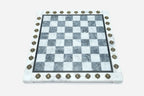 Overhead view of the polished grey marble chessboard with its brass-studded border