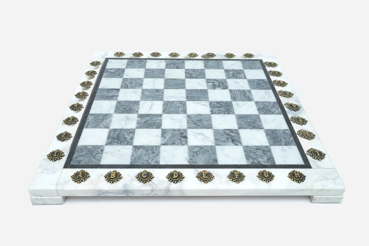 Front view of the grey and white marble chess board framed by brass coordinate markers