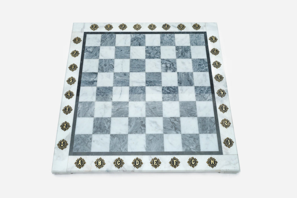Top-down view of the empty grey and white marble chess board with brass coordinate markers