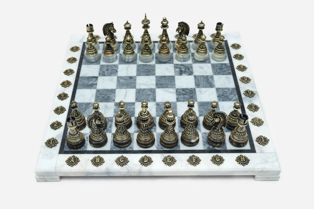 Grey and white marble chess set with hand-cast bronze pieces arranged for play and brass coordinate markers