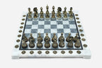 Grey and white marble chess set with hand-cast bronze pieces arranged for play and brass coordinate markers