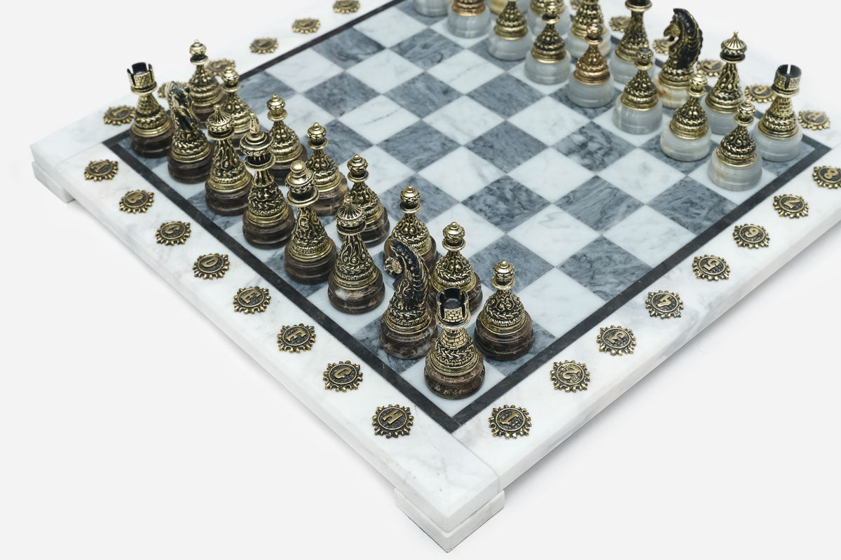 Detailed bronze chess pieces, including a dragon-style knight, on the grey and white marble squares