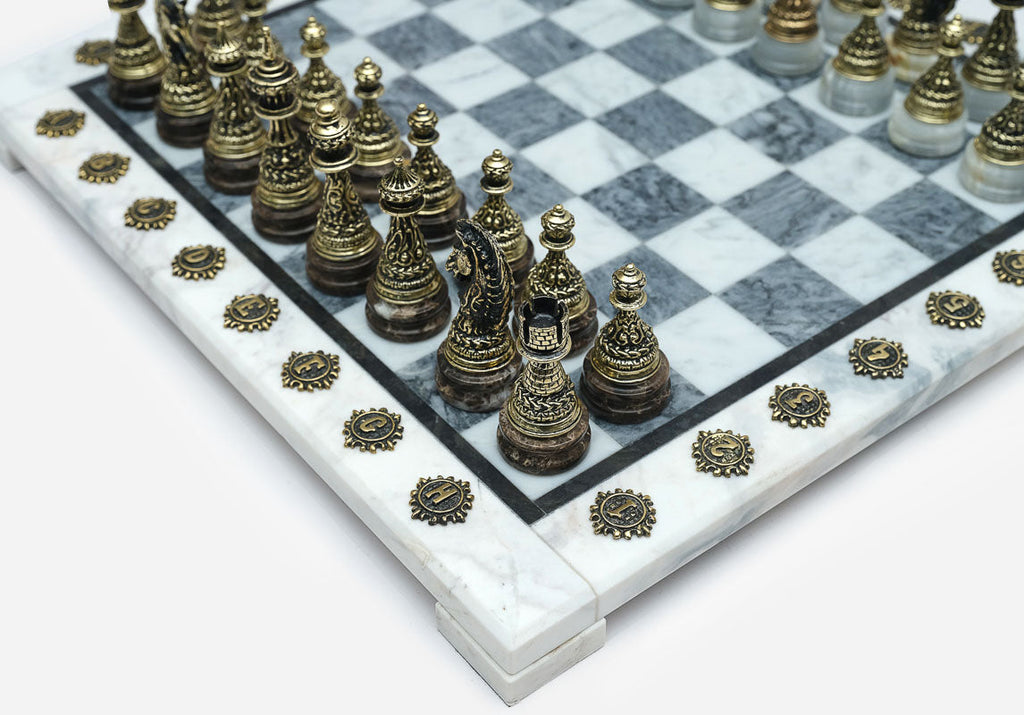 Close-up of the ornately cast bronze chess pieces on the grey marble board