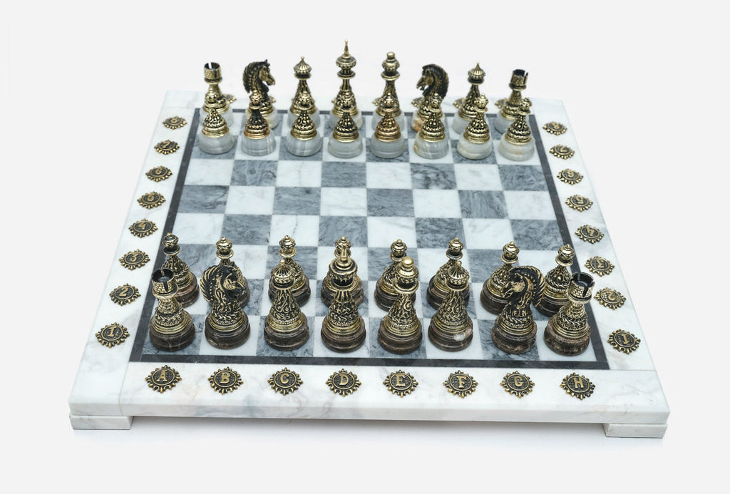Angled view of the grey marble chess board with detailed bronze pieces set up for play