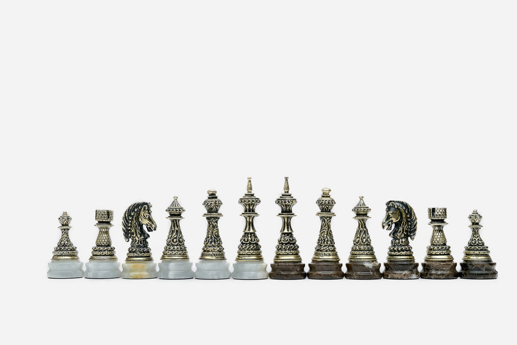 Full row of the hand-cast bronze chess pieces showing kings, queens, bishops and horse-head knights