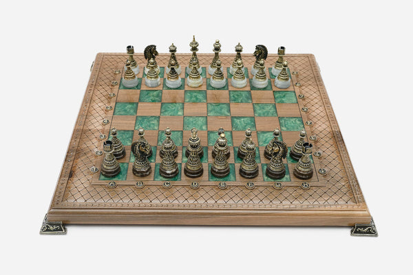 Chess board in walnut with green epoxy squares, brass corners and figural bronze pieces on marble bases set up for play