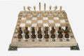 Chess board in pale wood with white marbled epoxy squares, brass corner brackets and wooden pieces set up for play