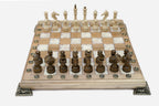 Chess board in pale wood with white marbled epoxy squares, brass corner brackets and wooden pieces set up for play