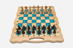 Folding chess board in pale wood with turquoise epoxy squares and ornately carved wooden pieces set up for play