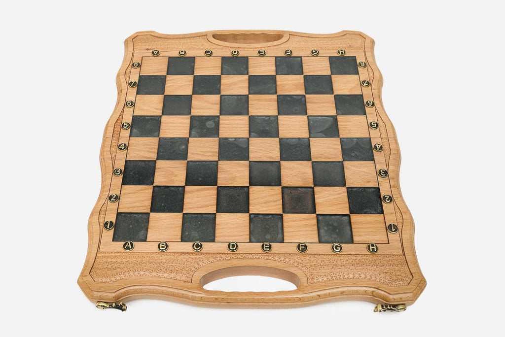 Close-up of the ornate bronze chess pieces on cream and walnut bases